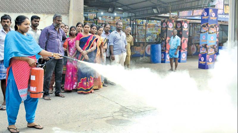 As part of an awareness campaign, a Triplicane Urban Cooperative Society (TUCS) employee demonstrates the method to use a fire extinguisher at Teynampet on Friday. (Photo: DC)
