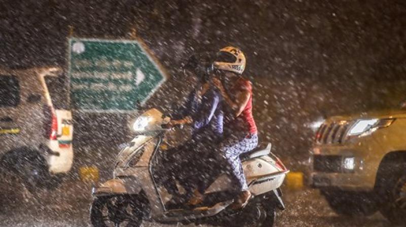 Commuters ride on a scooter during a thunderstorm in New Delhi on Wednesday. Change in the weather has brought respite in parts of Delhi and the National Capital Region (NCR) reeling under warm weather conditions for past days. (Photo: PTI)