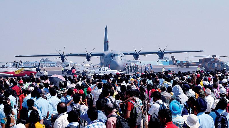 Visitors watch the flying display during Aero India 2017; and people at various stalls (right) at the event, at Yelahanka Airforce Station, in Bengaluru on Friday. (Photo: Shashidhar B.)
