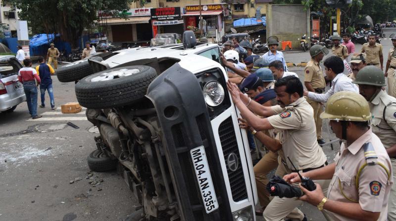 Police tries to set right a car that was overturned by protesters during the Mumbai bandh. (Photo: AP)