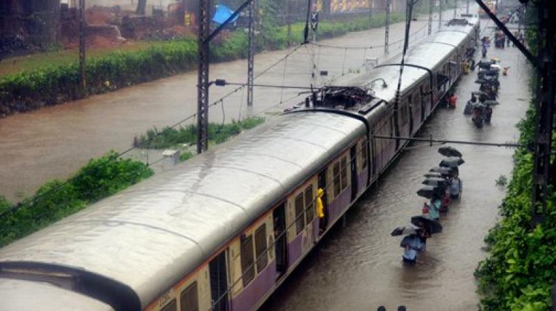 Commuters walk through rain waters along a local train after heavy rains lashed Mumbai on Tuesday.