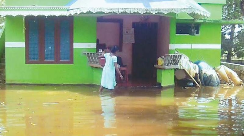 Manju K.V., Sakuntalas daughter-in-law, fetches water to clean their home, where water has receded from the rooms, on Monday