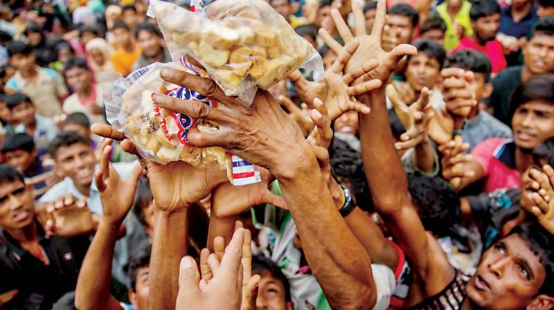 Rohingya Muslims, who crossed over from Myanmar into Bangladesh, stretch their arms out to receive packets of biscuits thrown at them as handouts. (Photo: AP)
