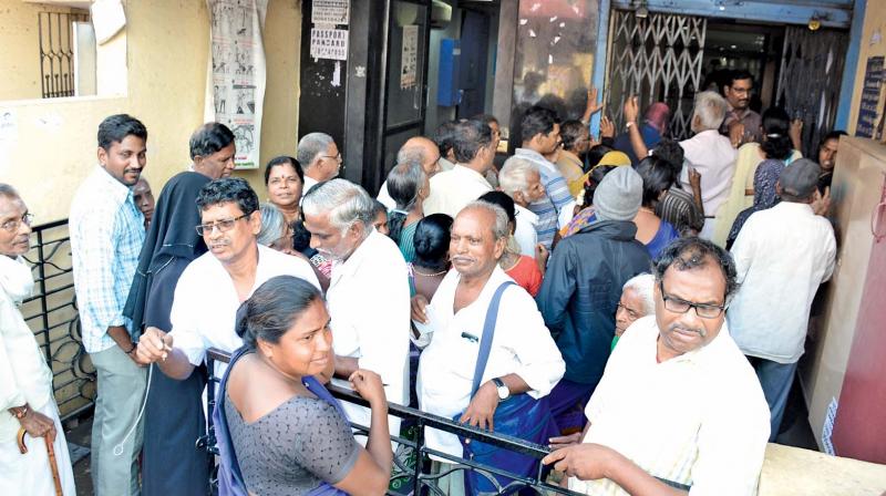 People wait before the Indian Bank branch at Ayanavaram to withdraw money on Saturday. (Photo: DC)