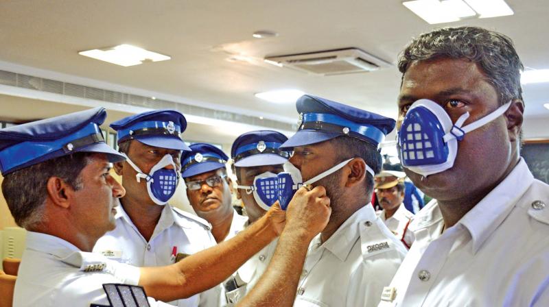 Traffic policemen try the N-95 mask distributed by Chennai police commissioner  A.K. Viswanathan on Tuesday. (Photo: DC)