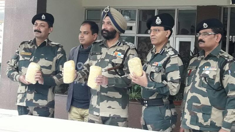 Officers hold the packets of heroin found around the border fence. (Photo: Twitter | @BSF_India)