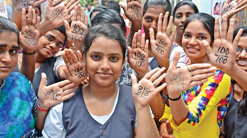 Students at one of the city schools write 100/100 on their hands to mark  100 per cent pass percentage.	(Photo: DC)