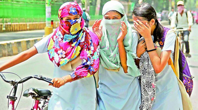 Girls cover their faces with scarves to protect themselves from the scorching heat in Allahabad on Monday. (Photo: PTI)