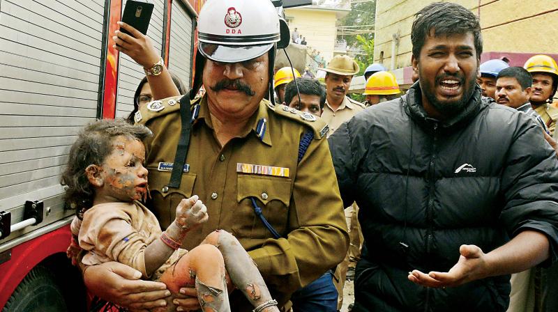 File photo of a fireman carrying Sanjana after she was pulled from the debris of a building at Ejipura in Bengaluru. Sanjana died from her injuries on Thursday