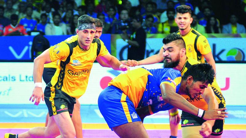 A Tamil Thalaivas player is trapped by Telugu Titans rival in the opening match of the Pro Kabaddi League at the Gachibowli Stadium in Hyderabad on Friday.