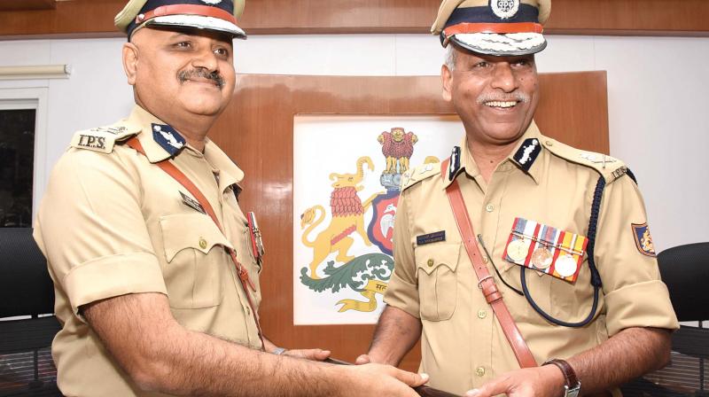 Outgoing Bengaluru Police Commissioner N.S. Megharikh handing over the baton to new City Police Commissioner Praveen Sood in Bengaluru on Sunday. (Photo: R. Samuel)