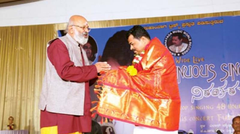 Pandit Prasanna Gudi being felicitated by actor Shivaram after the vocalist broke his own record.