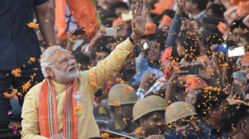 Prime Minister Narendra Modi waves to people during his road show in Varanasi. (Photo: PTI)