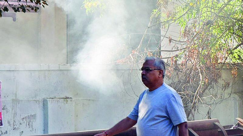 Residents suffer the smoke emanating from garbage set on fire by GHMC staff at OUs NSS Gate. (Photo: S. Surender Reddy)