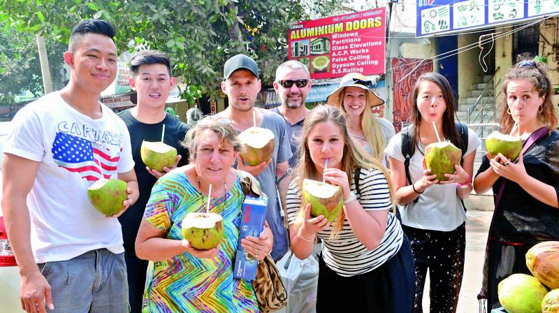 Foreign tourists enjoy tender coconut water on the Ramakrishna Beach in Visakhapatnam on Friday. (Photo: DC)