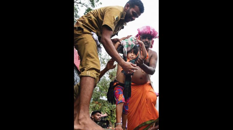 A policeman helps a child devotee climb up pathinettampadi  on Tuesday. (Photo: PTI )