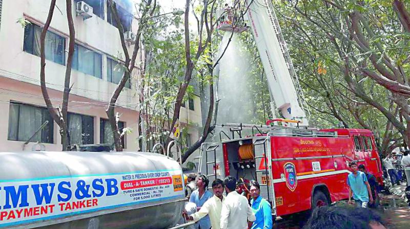 Fire service personnel try to put out the fire at the Andhra Jyoti office in the city on Saturday. (Photo: DC)