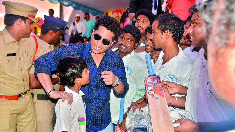 Cricketer and Rajya Sabha MP Sachin Tendulkar distributes cricket bats to youngsters at his adopted village P.R. Kandrika in Nellore district on Wednesday. (Photo: Deccan Chronicle)