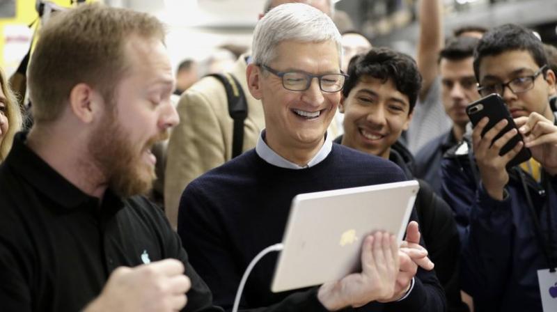 Apple CEO Tim Cook smiles as he watches a demonstration on an iPad at an Apple educational event at Lane Technical College Prep High School in Chicago. New iPads and Mac computers are expected Tuesday, Oct. 30, as part of an Apple event in New York. (AP Photo/Charles Rex Arbogast, File)