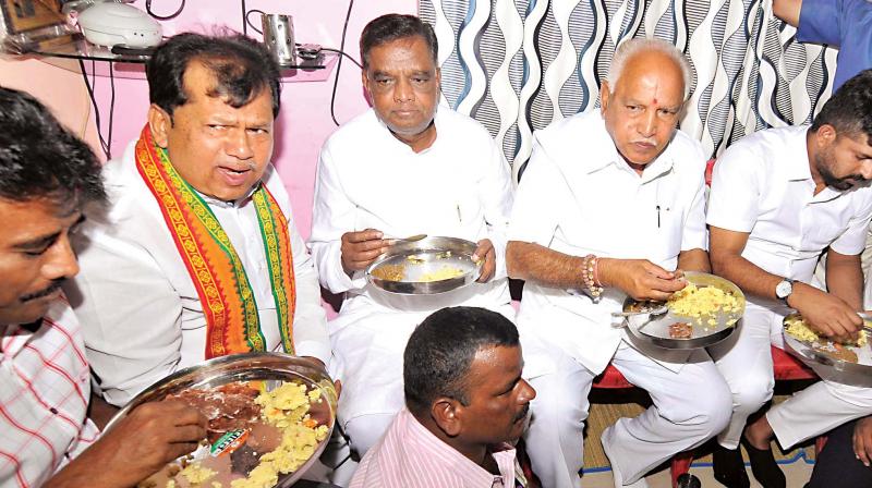 Senior BJP leaders B.S. Yeddyurappa and V. Srinivasprasad having breakfast at a Dalits house at Kesare in Mysuru on Sunday. (Photo: KPN)