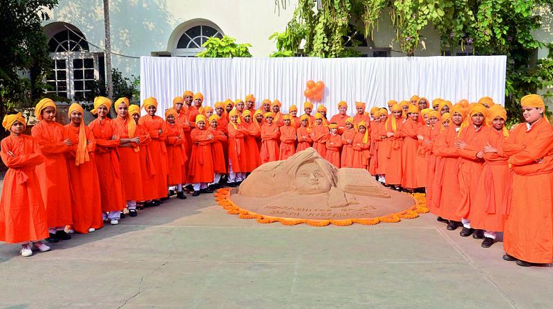Children dressed as Swamy Vivekananda stand around the sand sculpture on the 155th birth anniversary celebrations at Sri Prakash School in Visakhapatnam on Friday. (Photo: DC)