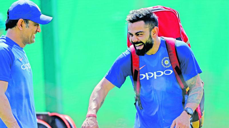 Mahendra Singh Dhoni (left) and Virat Kohli share a light moment at training. (Photo: AP)