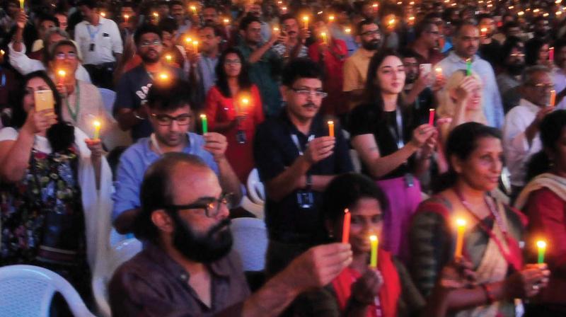 Delegates and dignitaries hold candles to pay respect to the victims of the flood faced by the state, during the inaugural function of 23rd IFFK on Friday.