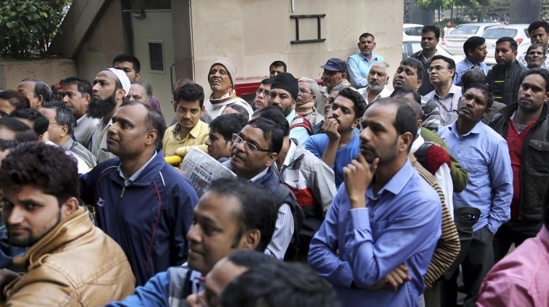 People wait outside a bank to withdraw money in New Delhi. (Photo: PTI)