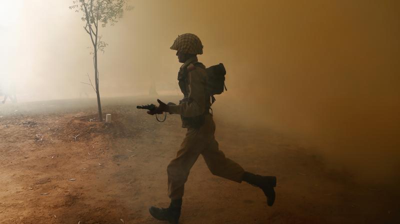 An Indian army soldier runs amid smoke from canisters during a session to showcase skills at the Army Service Corps training centre in Bangalore, India. (Photo)