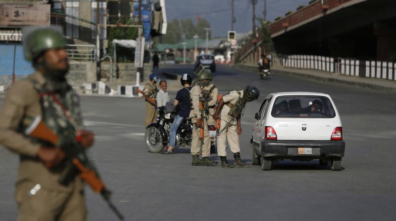 Paramilitary soldiers interrogate a civilian during a strike in Srinagar on Sunday. (Photo: AP)