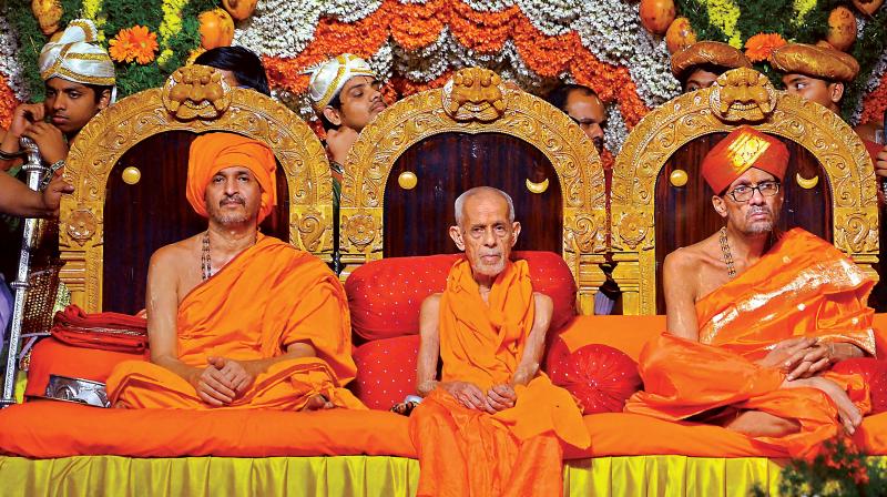 Outgoing Paryaya seer Vishwesha Teertha Swamiji (C) with his successor Vidyadheesha Tirtha Swamiji (L) of Pejawar Mutt at the ascending ceremony at Paryaya Darbar in Udupi on Thursday.	(Photo: PTI)