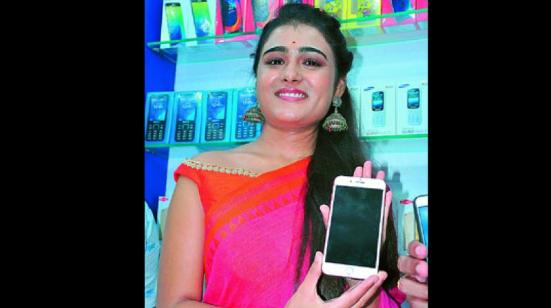 Arjun Reddy fame Shalini Pandey displays a mobile phone after inaugurationg a showroom.