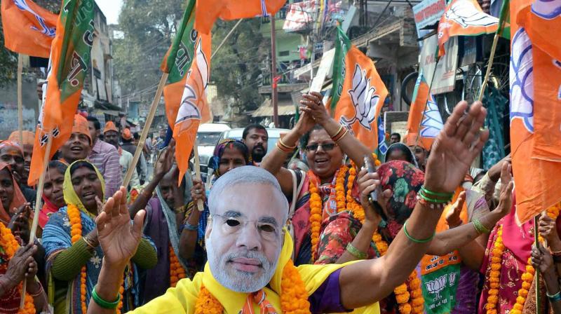 A woman supporter of BJP dances while wearing a mask of Prime Minister Narendra Modi at an election campaign. (Photo: PTI)