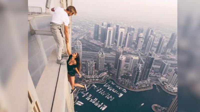 The video shows her stepping off a girder at the top of Dubais 73-storey Cayan Tower and dangling in the void, held only by a man gripping her hand.