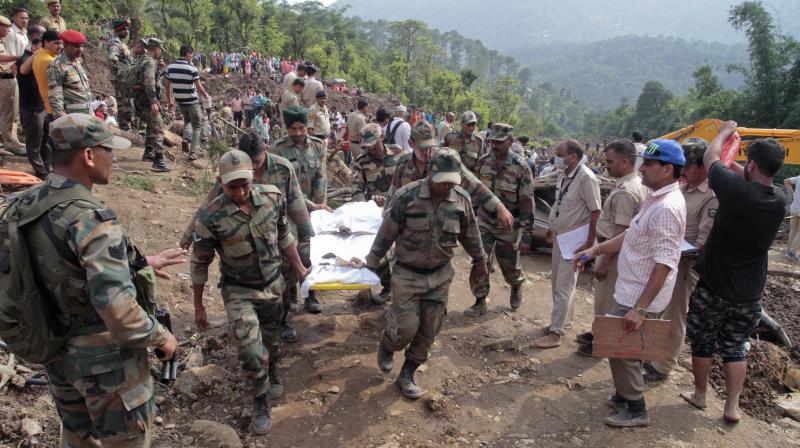 Army soldiers and rescue workers recover bodies of landslide victims even as they try to pull out two buses that were covered in mud after a landslide triggered by heavy monsoon rain in Urla village, Himachal Pradesh. (Photo: AP)