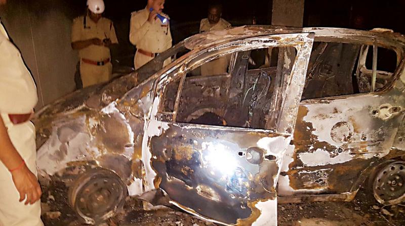 The remains of the car that was burnt after it suddenly caught fire at Samadhur Apartment in Whitefield on Friday. A woman, Neha Verma and her two-year-old son Param, died in the mysetrious fire. (Photo: DC)