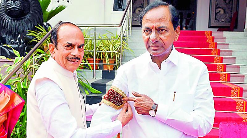 TRS MLC Mahmood Ali ties a band on Mr K. Chandrasekhar Rao arm before his swearing- in on Thursday.  (DC)