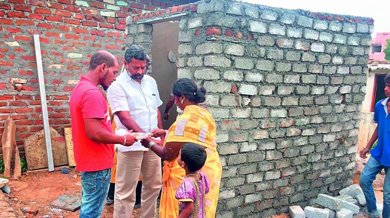 Reshma, 28, ties rakhi to her brother G. Sripal Reddy against the backdrop of the underconstruction toilet that was gifted to her this Raksha Bandhan.  (Photo:DC)