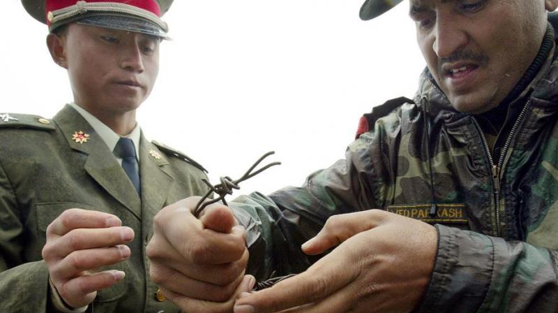 This file photo taken on July 5, 2006 shows a Chinese soldier (L) and Indian soldier placing a barbed wire fence following a meeting of military representatives at the Nathu La border crossing. (Photo: AFP)
