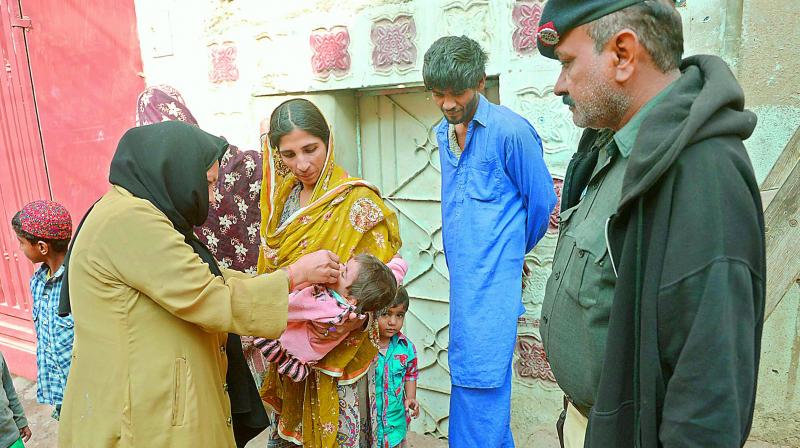 Pakistani health administer gives Polio drops to an infant.