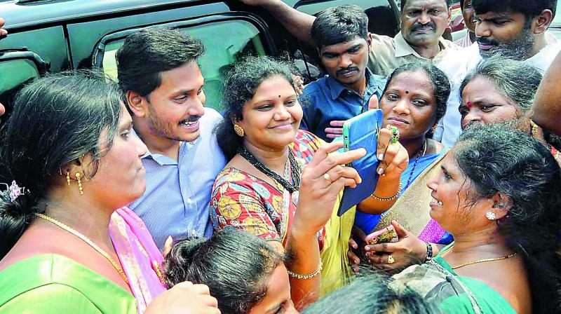 Women activists of the YSRC take a selfie with party president Y.S. Jagan Mohan Reddy as he arrives at Visakhapatnam Airport while on his way to Srikakulam district on Friday. (Photo: DC)