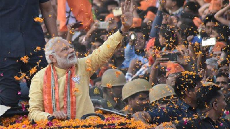 Prime Minister Narendra Modi waves to people during his road show in Varanasi on Sunday. (Photo: PTI)