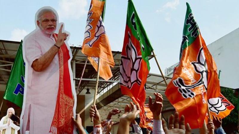BJP workers carry a giant cut-out of Prime Minister Narendra Modi as they celebrate the partys victory in the UP and Uttarakhand Assembly elections, at the party headquarters in New Delhi. (Photo: PTI)