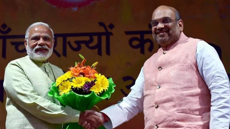 Prime Minister Narendra Modi greets BJP President Amit Shah at the party headquarters to celebrate victory in UP and Uttrakhand Assembly elections, in New Delhi on Sunday. (Photo: PTI)
