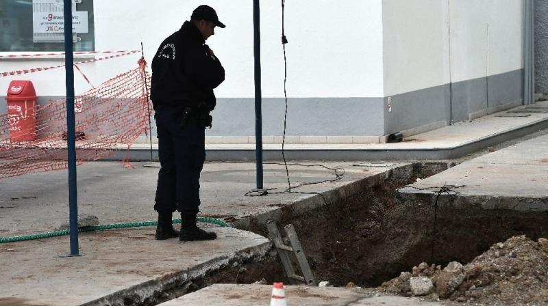 A policeman looks into a hole in Thessaloniki, northern Greece where an unexploded World War II bomb was found during work to expand a petrol stations underground tanks on February 8. (Photo: AFP)