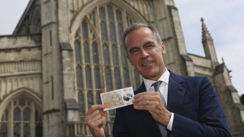 The Governor of the Bank of England, Mark Carney poses with the new 10 pound note featuring the image of Jane Austen, during the unveiling ceremony, at Winchester Cathedral, in Winchester, England, Tuesday July 18, 2017. Two hundred years to the day since Jane Austen was laid to rest at Winchesters grand cathedral, Bank of England Governor Mark Carney has unveiled a new 10-pound note that features one of Britains most-loved authors. (Steve Parsons/PA via AP)