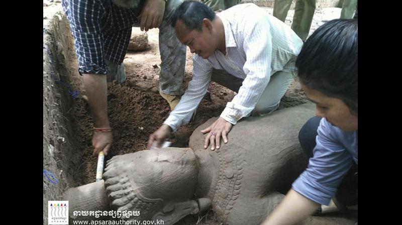 In this July 30, 2017, image made available by the Apsara Authority of the Cambodian Government, archaeologists examine a 1.9-meter (6-foot, 3-inch) tall, 58-centimeter (23-inch) wide statue at Angkor Wat in Siem Reap, Cambodia. Working with experts from Singapores Institute of Southeast Asian Studies, the Apsara Authority said the 12th or 13th century statue is one of the largest to be unearthed in recent years. (Apsara Authority via AP)