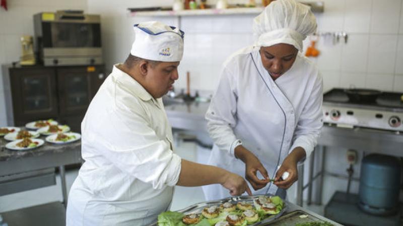 In this Tuesday, Oct. 10, 2017 photo, Khaled Maghary, 25, receives instructions from a trained specialist, as he prepares a dish at a restaurant in Rabat, Morocco. (Photo: AP)