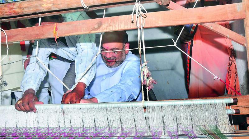 BJP national president Amit Shah gets a a feel of the loom at a weavers residence during his tour of Nalgonda district on Monday. (Photo: Deccan chronicle)