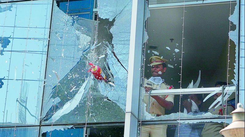 Police and firefighting personnel break the glasses of a window at Sentini Hospital in Vijayawada after fire erupted on the premises on Tuesday. (Photo: DC)